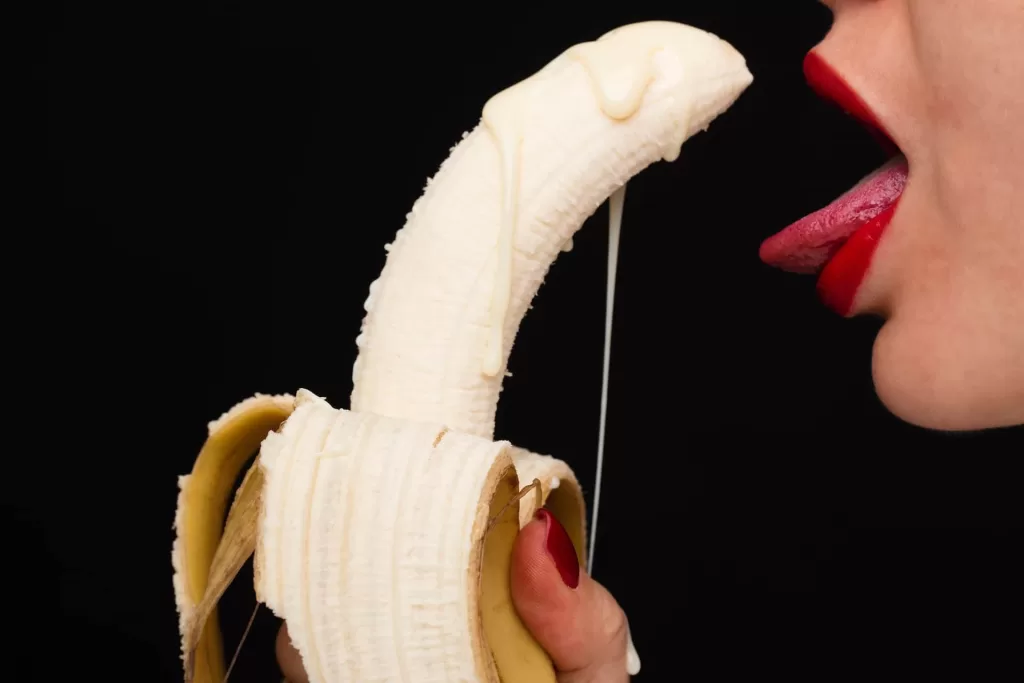 Banana dripping cream in front of woman's mouth