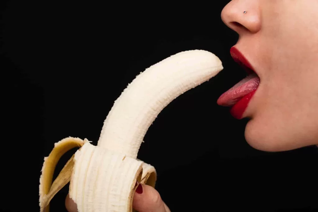 woman holding banana in front of her mouth representing a blowjob